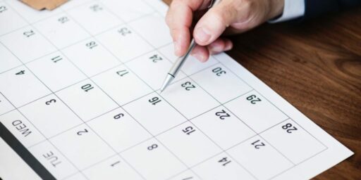 hand pointing to date on calendar with pen